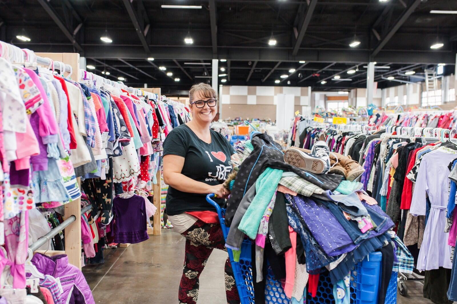 A mom and her child hug in between two rows of little girl clothes